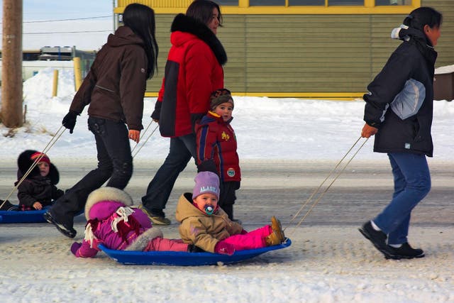 Inuit women pull their children on sledges in the arctic village of Kuujjuaq