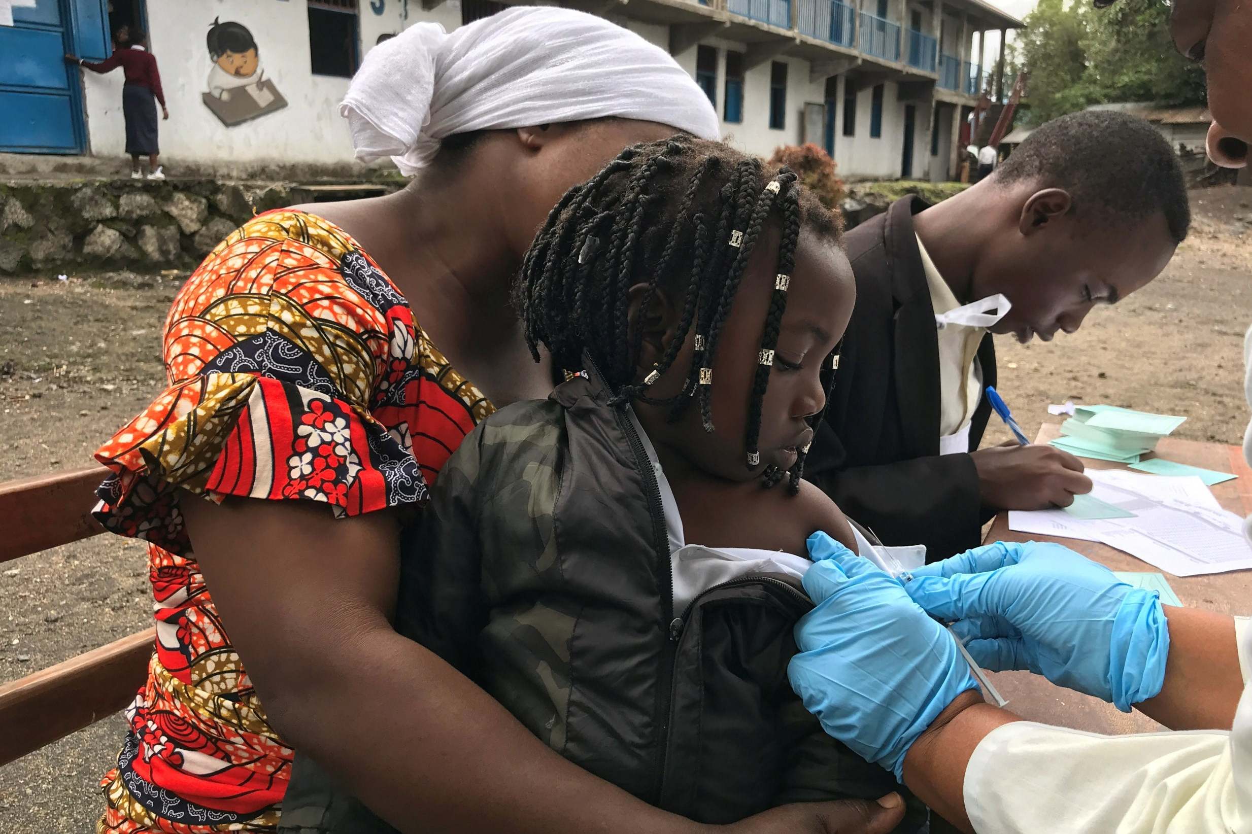 Health workers vaccinate a girl against measles at a school in eastern Congolese town of Goma