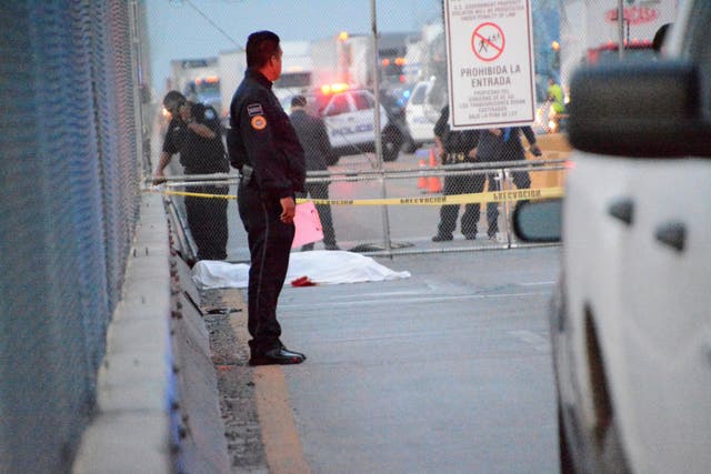 Police officers keep watch at the crime scene where a Mexican asylum-seeker slit his own throat after being denied entry into the United States