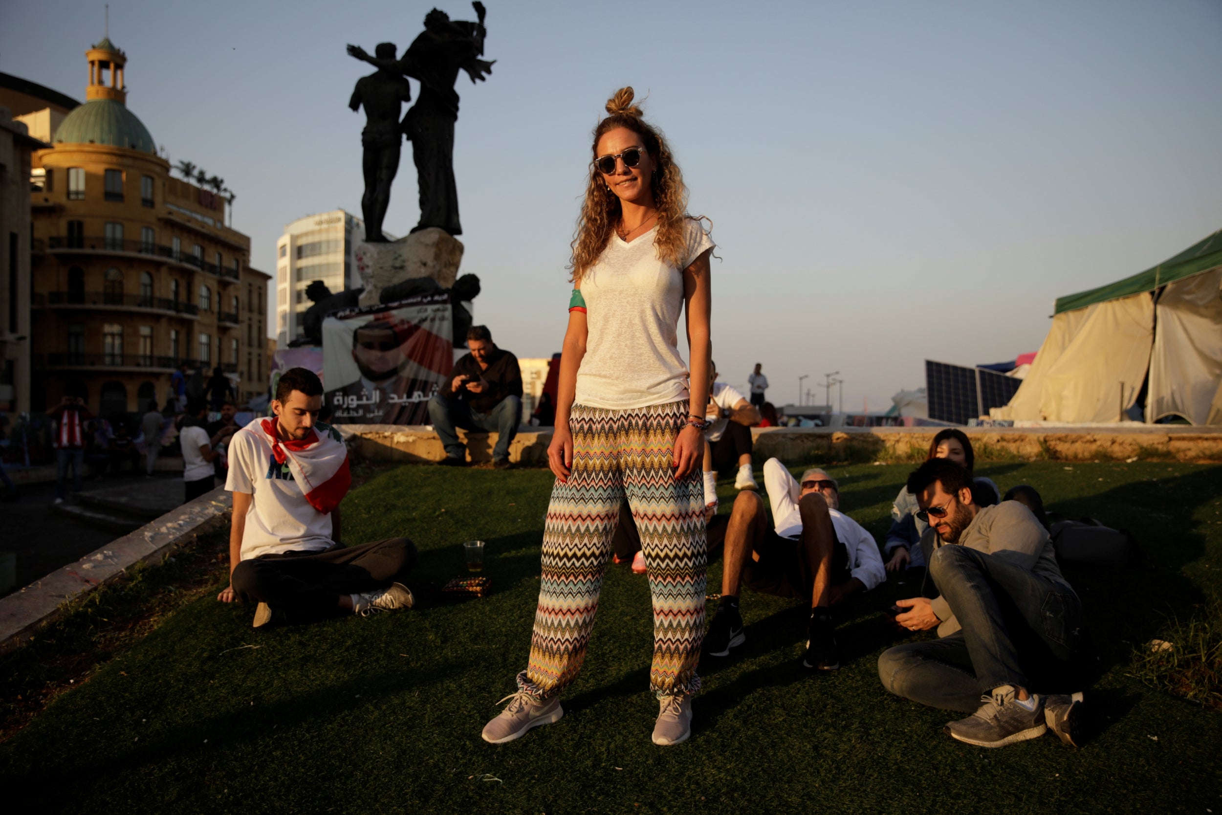 Hiba Ghosn, 36, who works in the fashion industry, poses as her friends sit in the afternoon sun on Martyrs’ square, as people gather for a demonstration during ongoing anti-government protests in Beirut, Lebanon