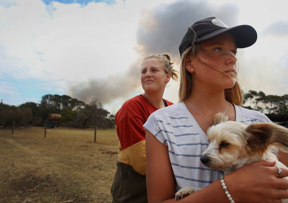 Bonnie Morris and sister Raemi Morris look on as their family and CFS firefighters battle bushfires at the edge of their family farm in Karatta, on Saturday