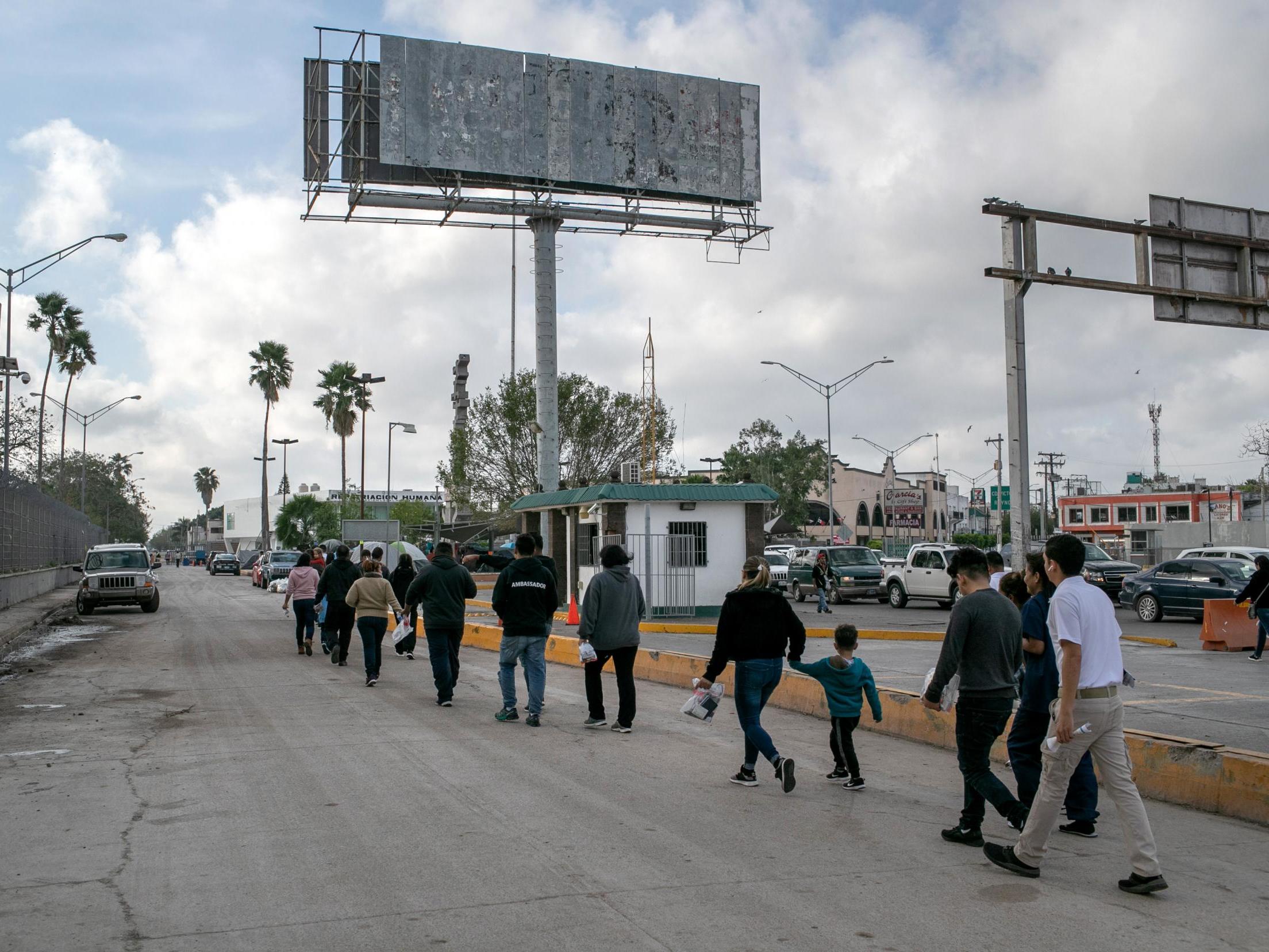 Asylum-seekers walk back into Mexico after their immigration court hearing on 9 December in Brownsville, Texas