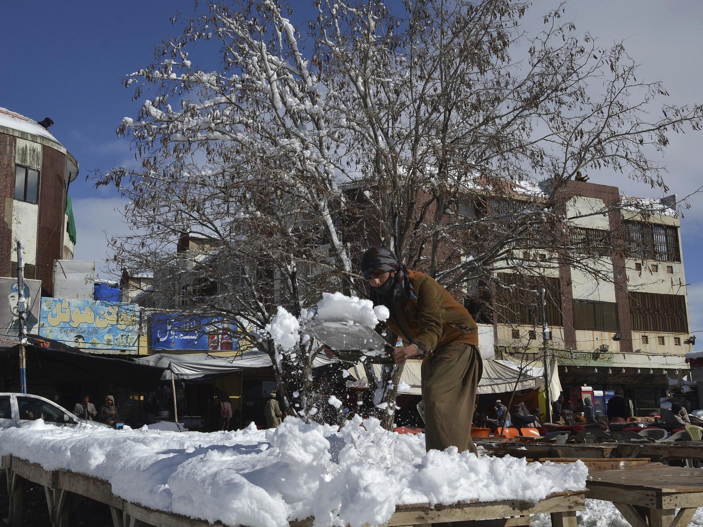 A vendor removes snow from his stall after heavy snowfall in Quetta, capital of Pakistan’s southwestern Baluchistan province, 13 January (AP)