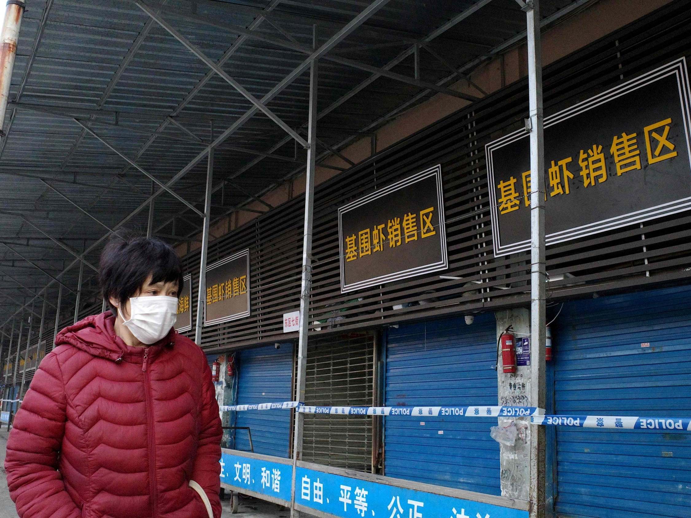 A woman walks in front of the closed Huanan wholesale seafood market, where health authorities say a man who died from a respiratory illness had purchased goods from, in the city of Wuhan