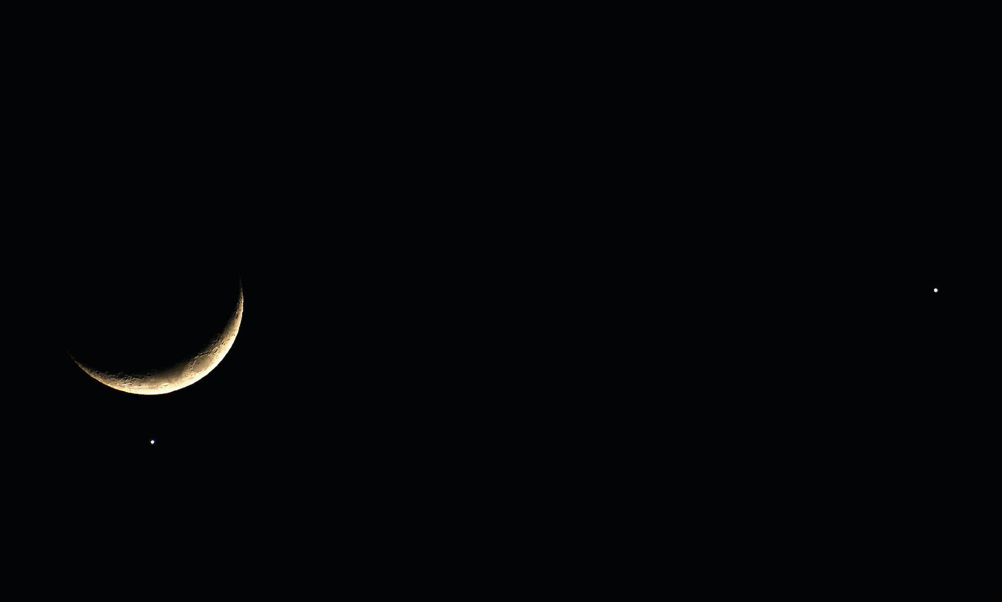 The planet Venus appears close to the crescent Moon as Jupiter (R) appears nearby during a rare planetary alignment on December 1, 2008 in Brighton, England