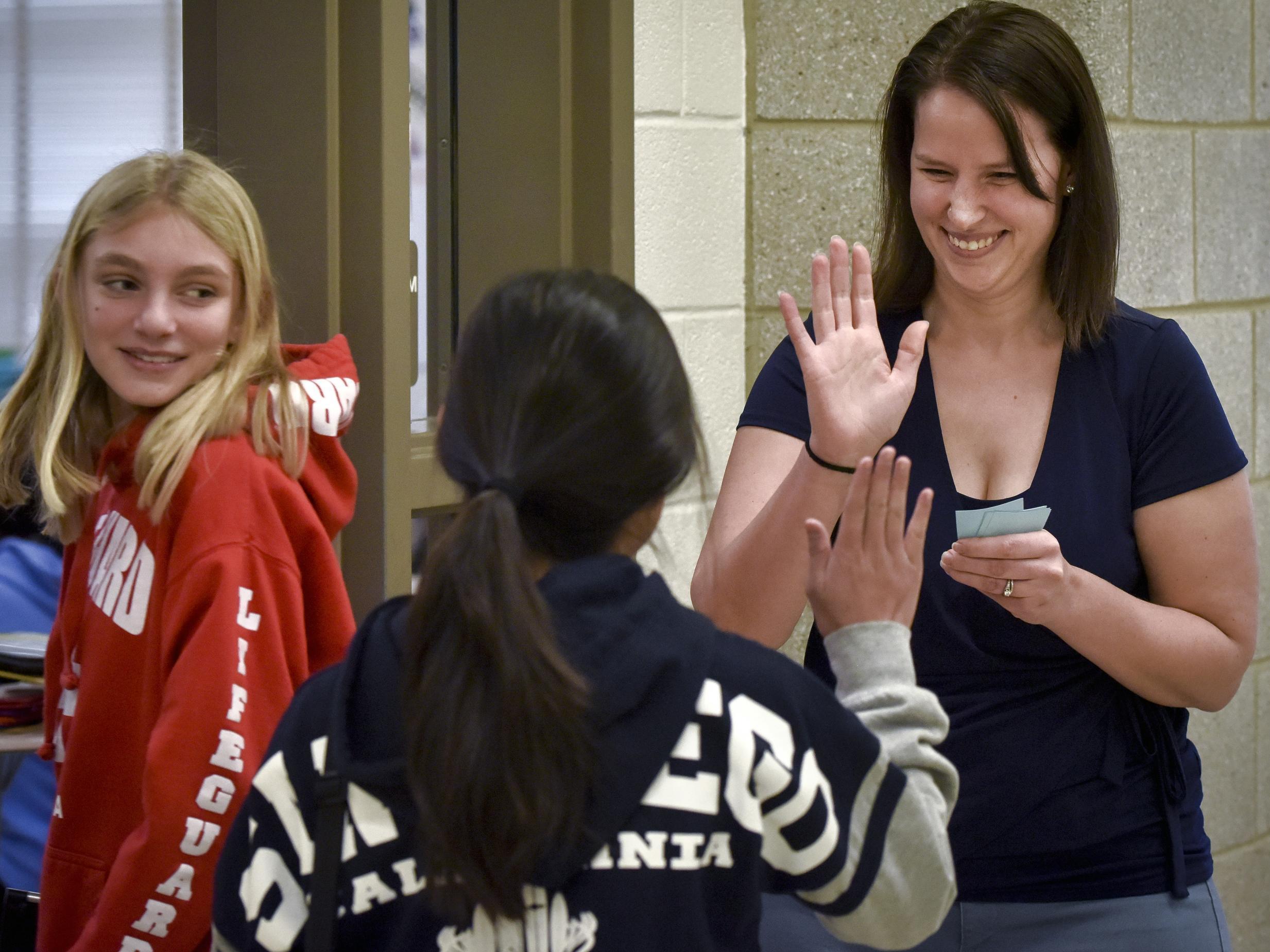 Students greet health teacher Courtney Marcoux with a high five as they enter her classroom at Hallie Wells Middle School in Clarksburg (Bill O'Leary/Washington Post)