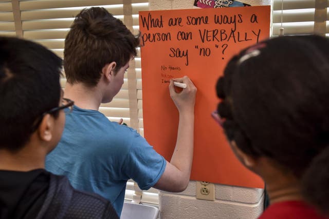 Students write their thoughts on a poster in response to a question about consent during health class at Hallie Wells Middle School in Clarksburg Bill O'Leary