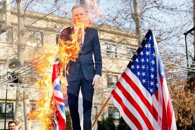 Iranian hardliners burn a cutout poster depicting British ambassador Robert Macaire along with British and US flags