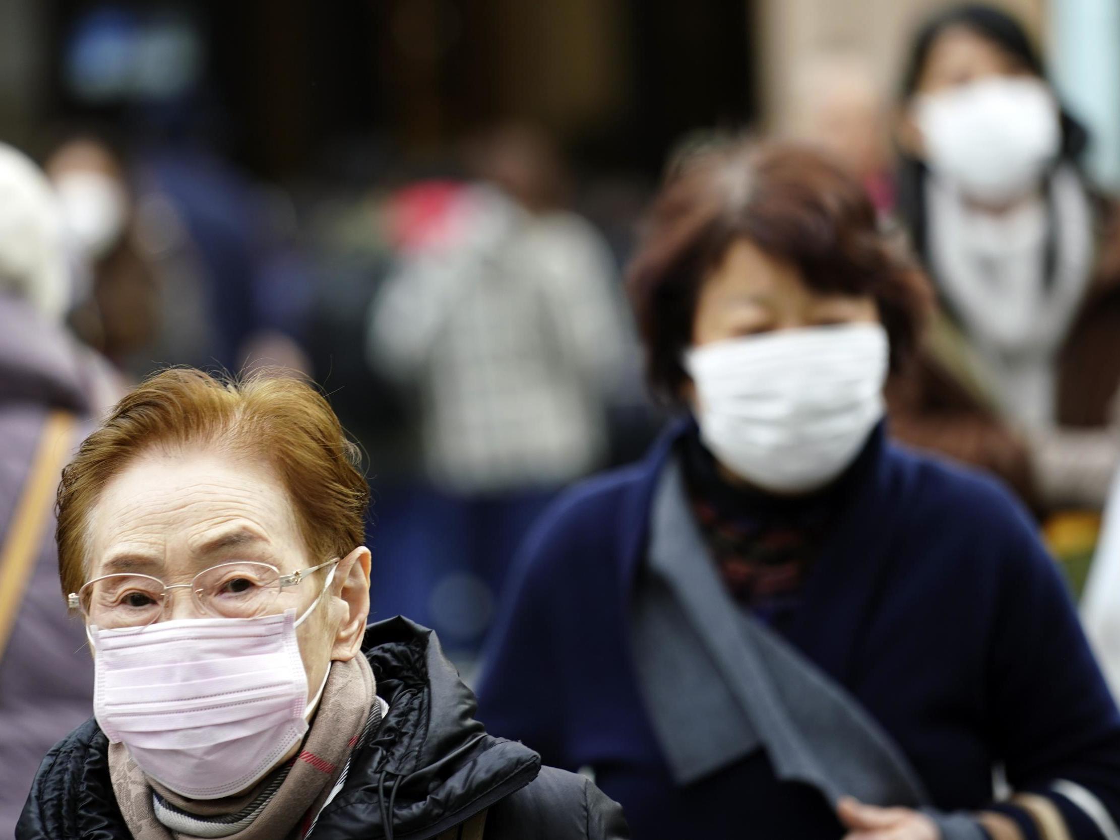 Pedestrians wear protective masks in Japan, where authorities discovered a patient infected with a Chinese coronavirus.