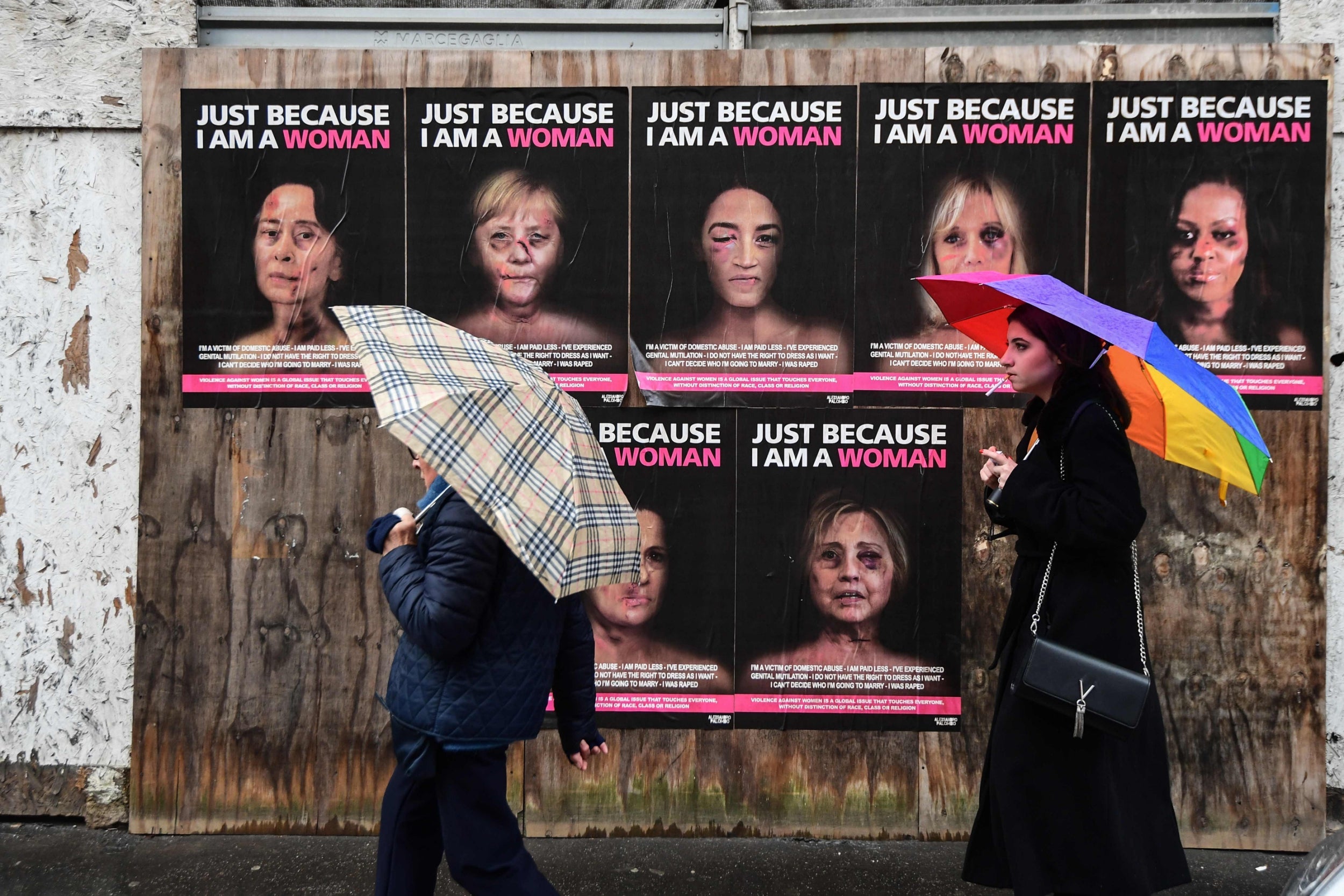 People walk past ‘Just because I am a Woman’, a new series of works by Italian artist aleXsandro Palombo, depicting women in politics as victims of gender violence