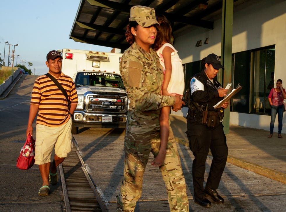 Jose Gonzalez, left, follows his 5-year-old daughter, carried by a police officer, as they leave a hospital in Santiago, Panama. Gonzalez's wife and five of their children are among seven people killed in a religious ritual in the Ngabe Bugle indigenous community