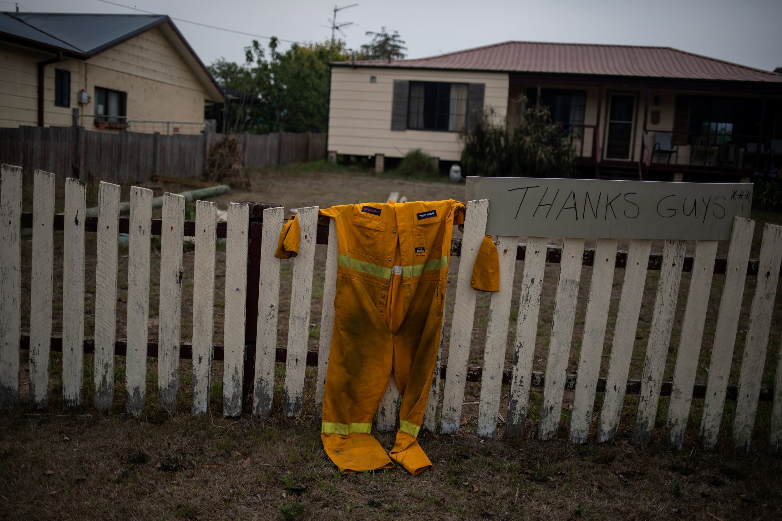 A firefighter’s suit hangs on the fence of a property