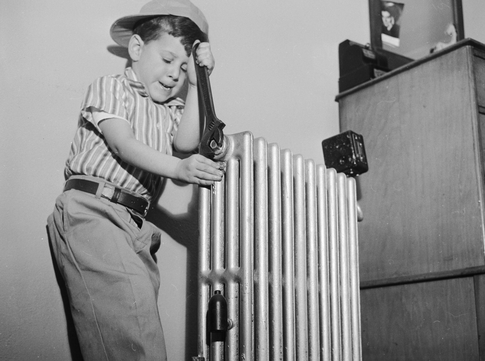 Four year old Morgan Layton tackles the radiator during his somewhat inexpert do-it-youself debut at his home in White Mains, New York