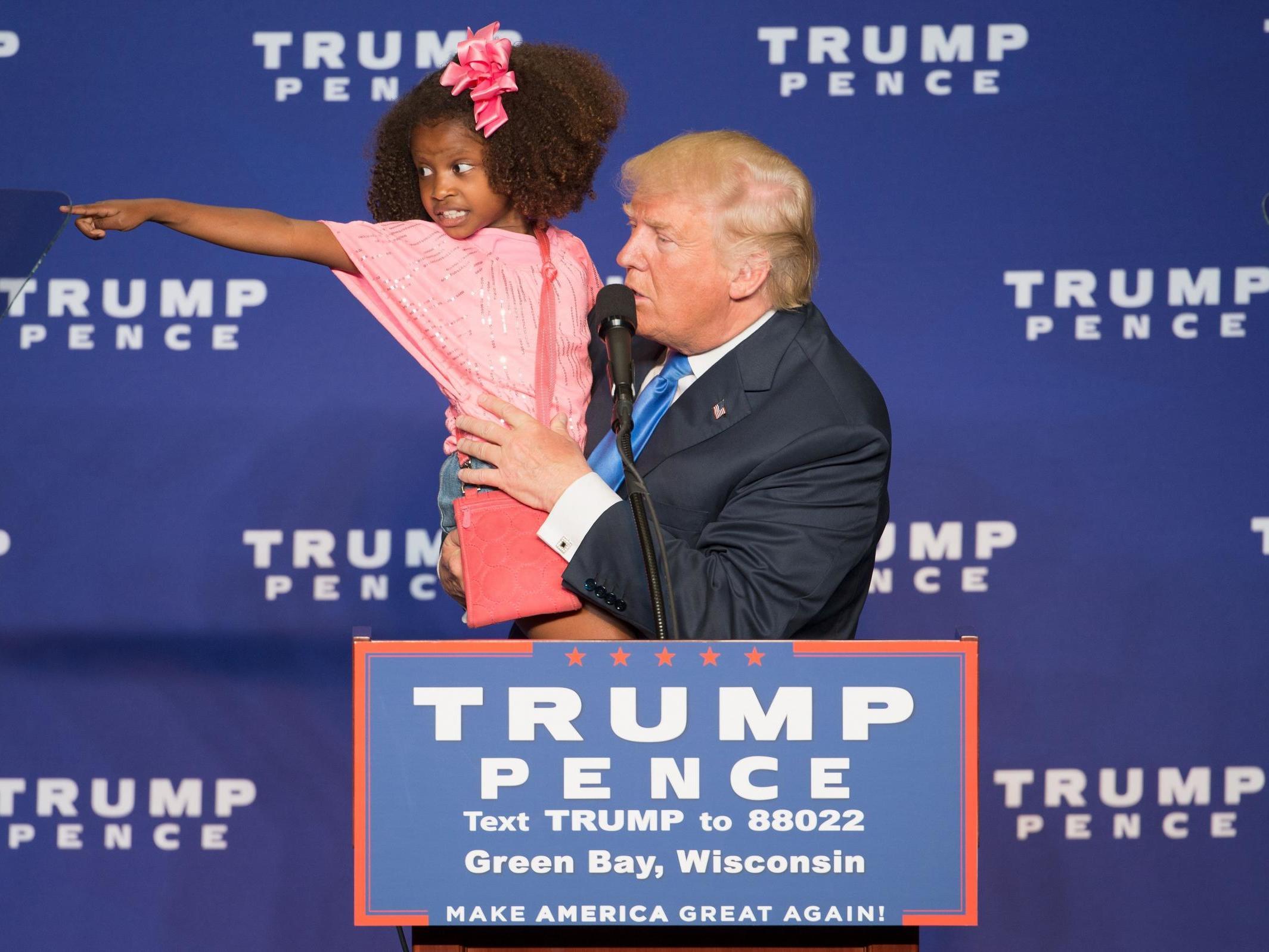 Republican presidential nominee Donald Trump holds a child as he speaks during a rally at the KI Convention Center on October 17 2016 in Green Bay Wisconsin