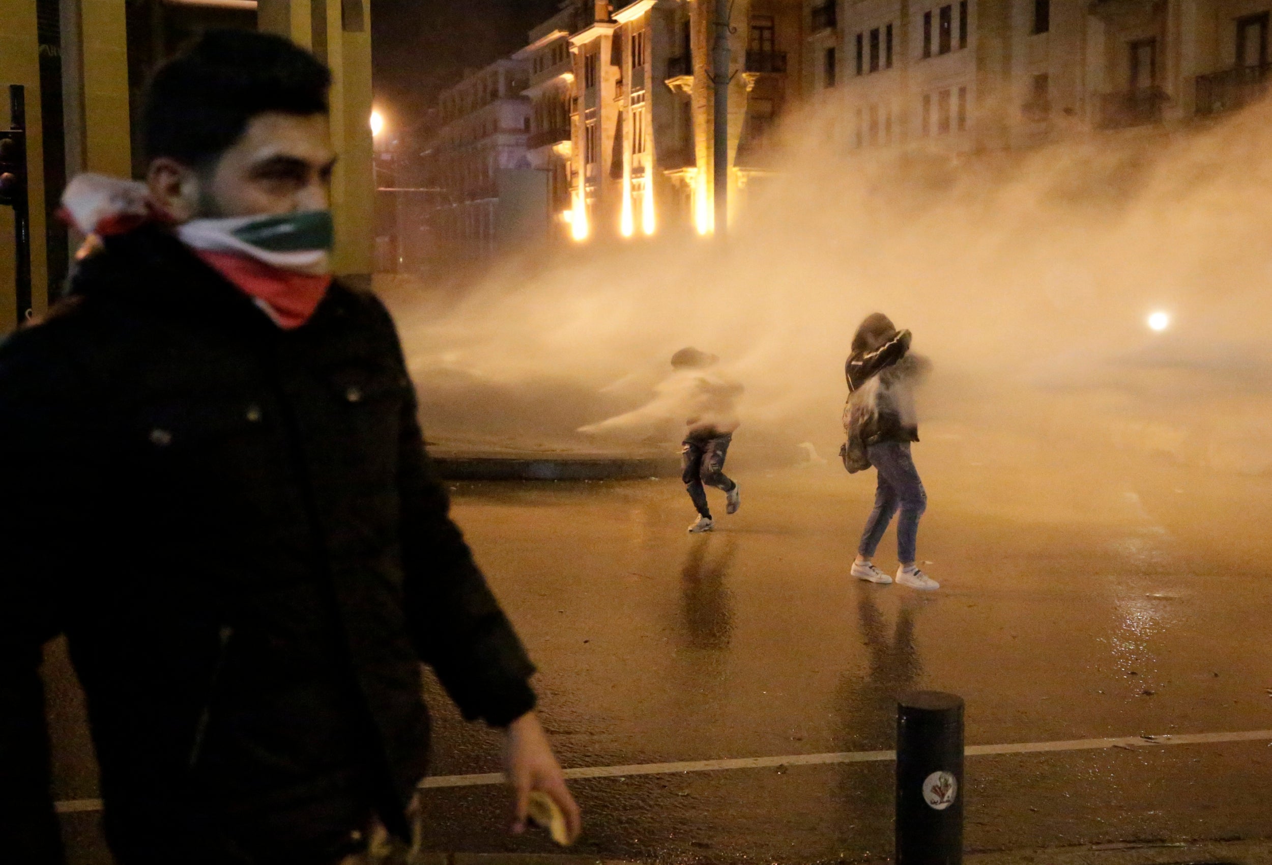 Protesters are sprayed by a water canon in Beirut