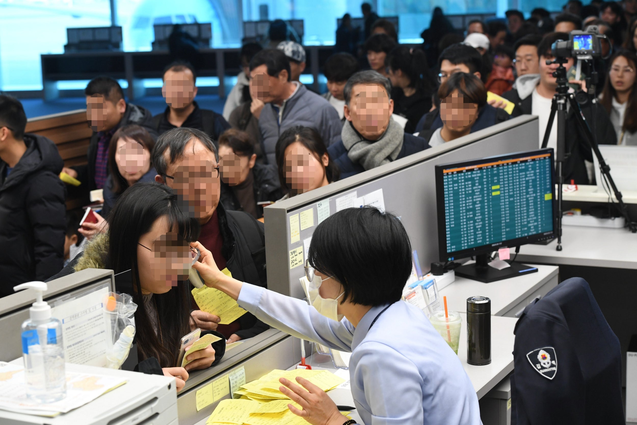 A quarantine officer at Incheon International Airport, South Korea, uses an electronic thermometer to check the temperature of passengers arriving by plane from Wuhan