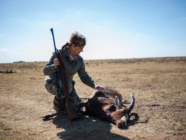 A hunter kneels by the body of an antelope she killed on a South African game reserve ( Getty )