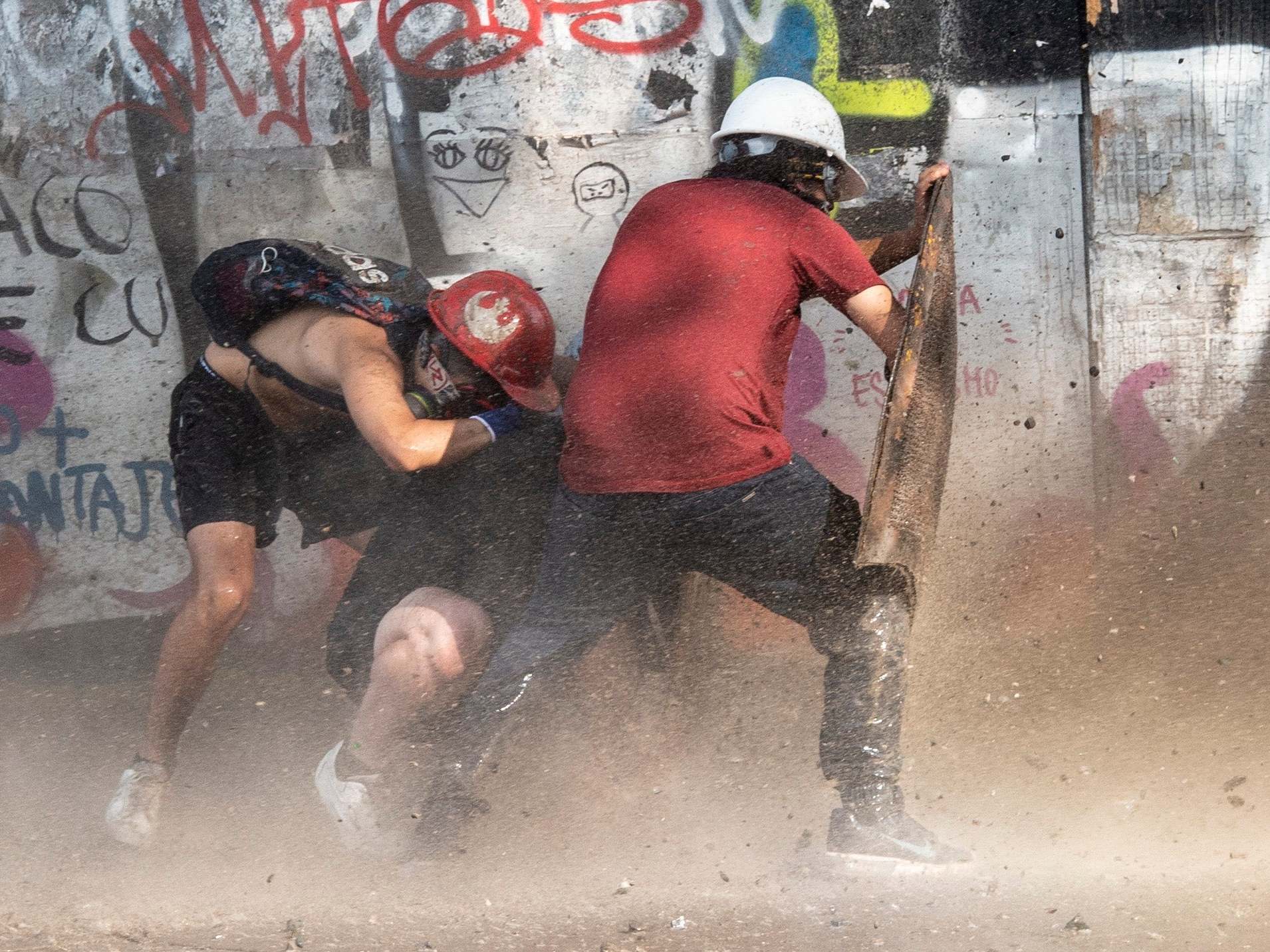 Demonstrators take cover as they clash with riot police during a protest against the government