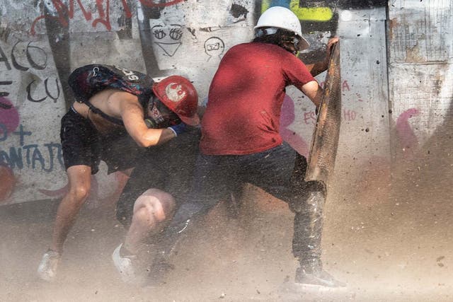 Demonstrators take cover as they clash with riot police during a protest against the government