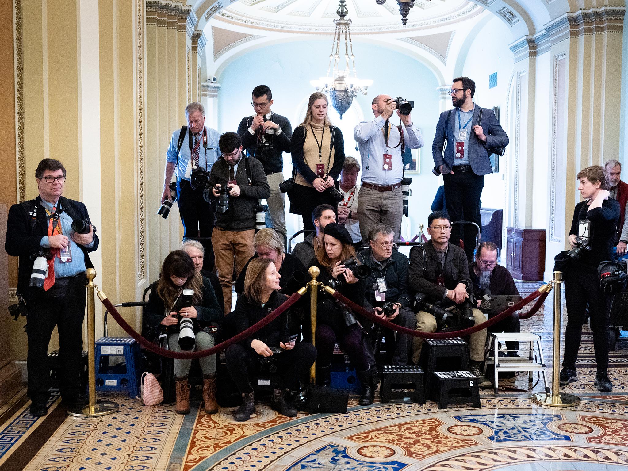 Press photographers covering the trial are confined to a small enclosure