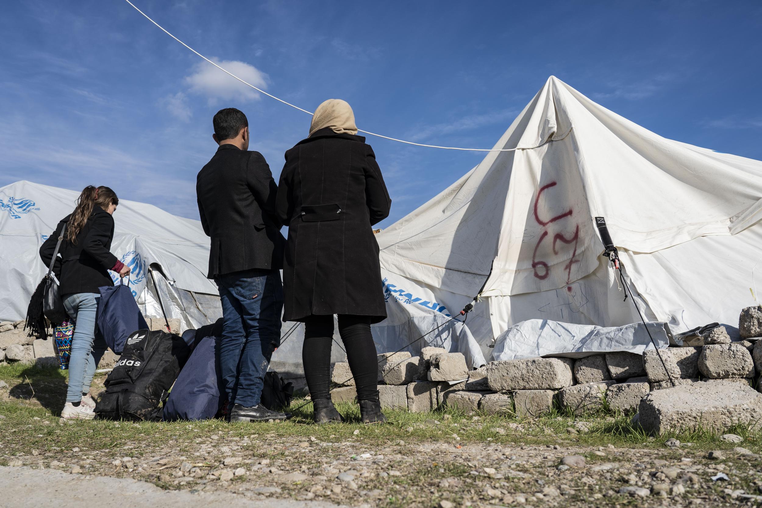 A couple who recently fled conscription in northern Syria stand outside the tent assigned to them