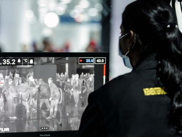 A Health official checks passengers going through a thermal scanner upon their arrival