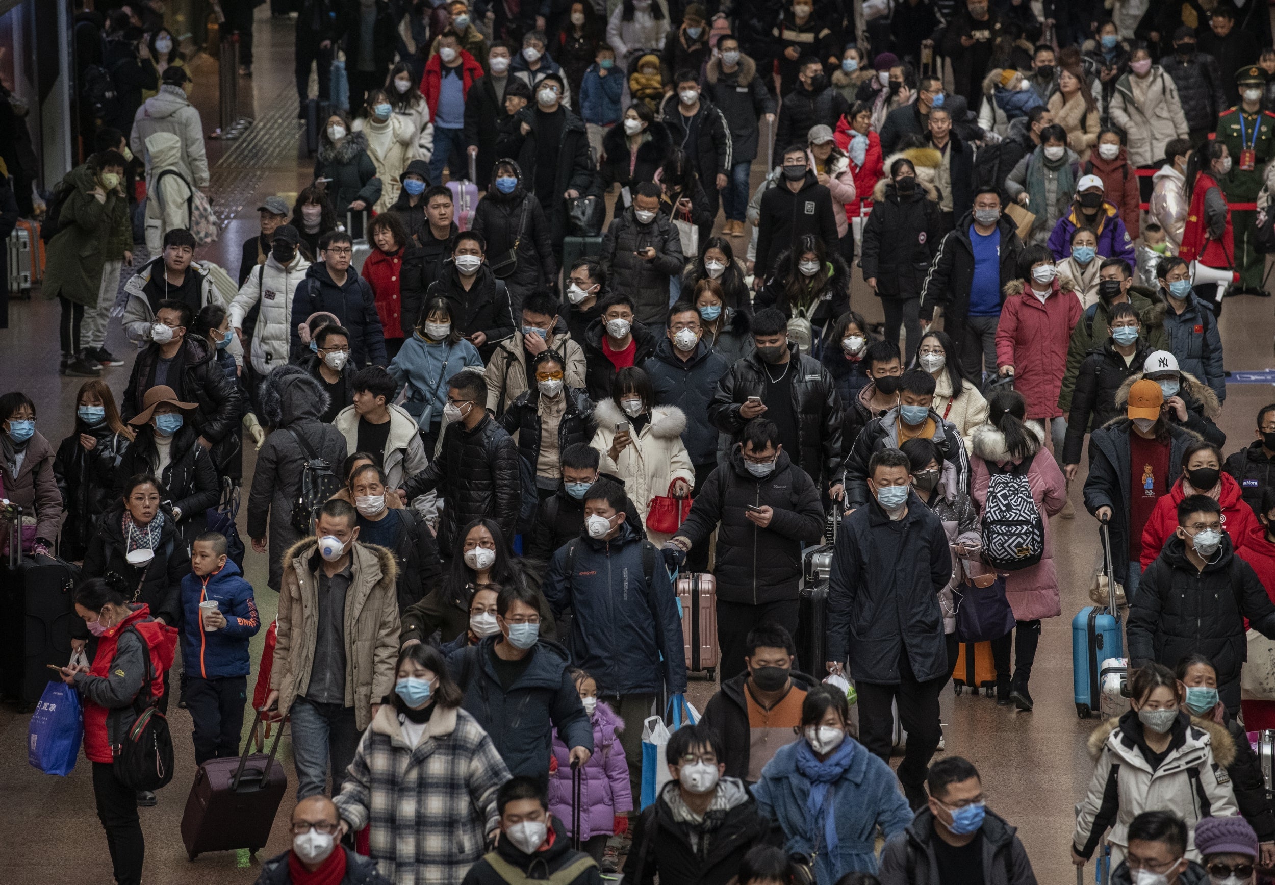 Chinese passengers, most wearing masks, arrive to board trains before the annual spring festival at a Beijing railway station on 23 January 2020