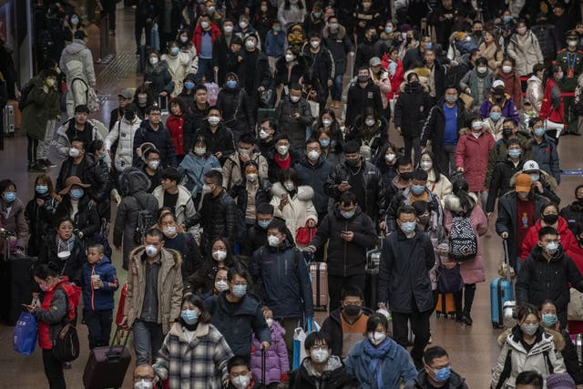 Chinese passengers, most wearing masks, arrive to board trains before the annual spring festival at a Beijing railway station on 23 January 2020
