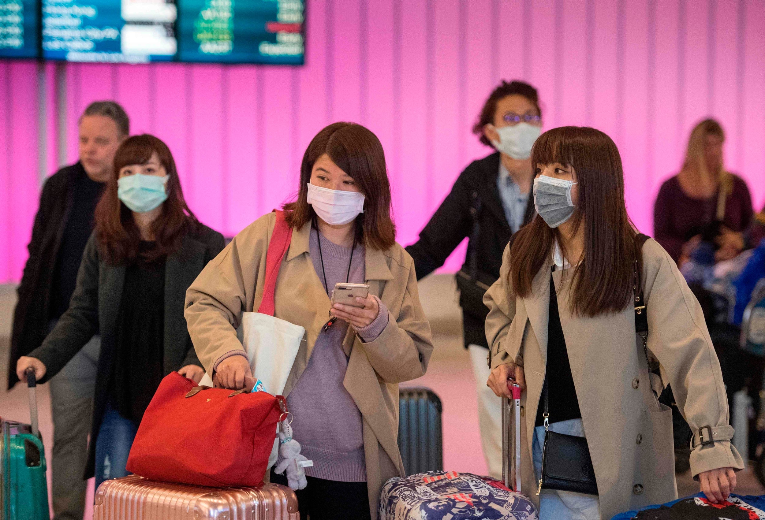 Passengers wear protective masks to protect against the spread of the Coronavirus as they arrive at the Los Angeles International Airport, California