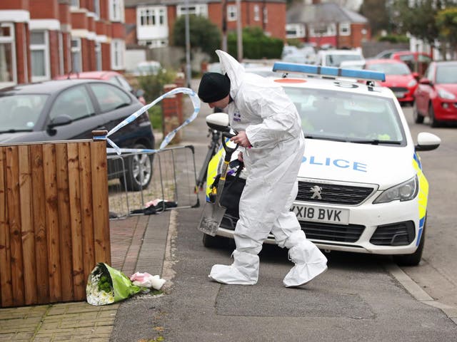Forensics officers try to work out what caused the blaze at the house where flowers were laid