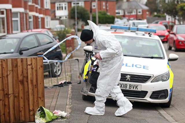 Forensics officers try to work out what caused the blaze at the house where flowers were laid