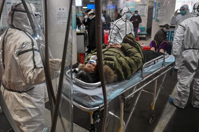 Medical staff members wearing protective clothing to help stop the spread of a deadly virus which began in the city, arrive with a patient at the Wuhan Red Cross Hospital in Wuhan on 25 January