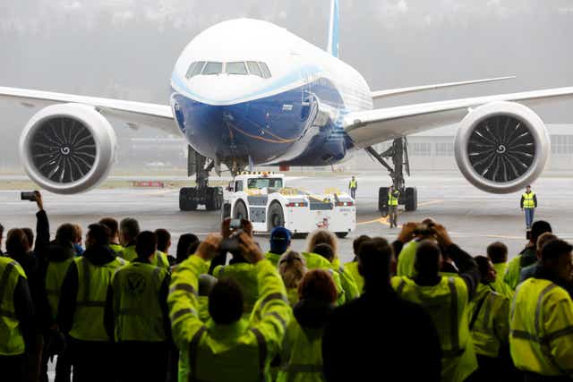 Boeing employees and others watch a Boeing 777X airplane return to a hangar after its first test flight