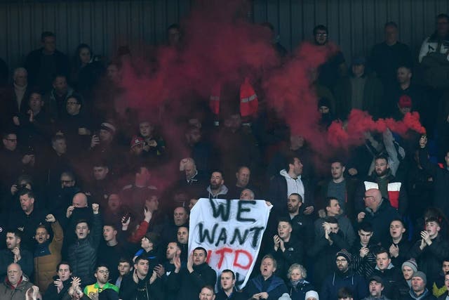 Supporters hold a banner which reads: 'We want Utd back'