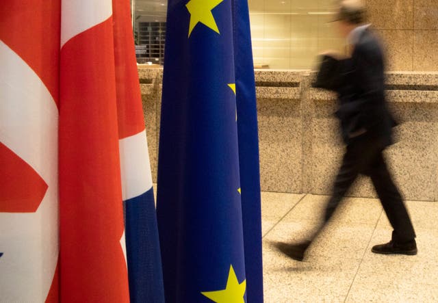 A man walks by the Union Flag and the EU flag inside the European Council building in Brussels