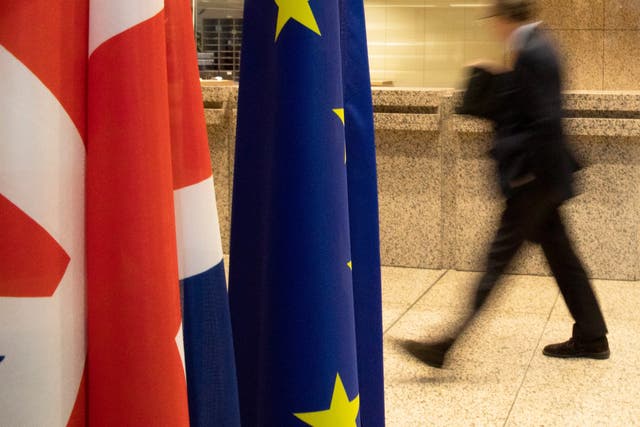 A man walks by the Union Flag and the EU flag inside the European Council building in Brussels