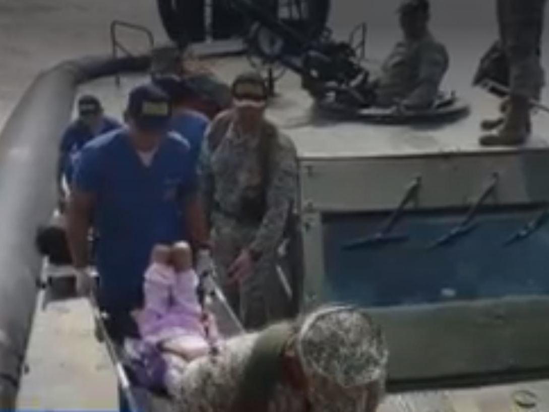 Rescue teams transport the mother and children off the hovercraft after they were found in a jungle between Peru and Colombia