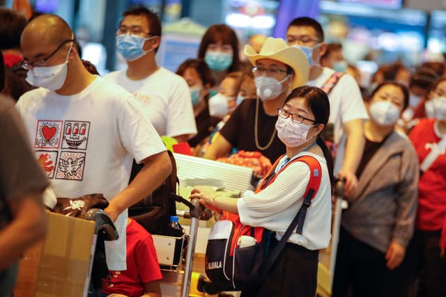 Chinese tourists wearing protective masks wait in line at Don Mueang airport in Bangkok, Thailand