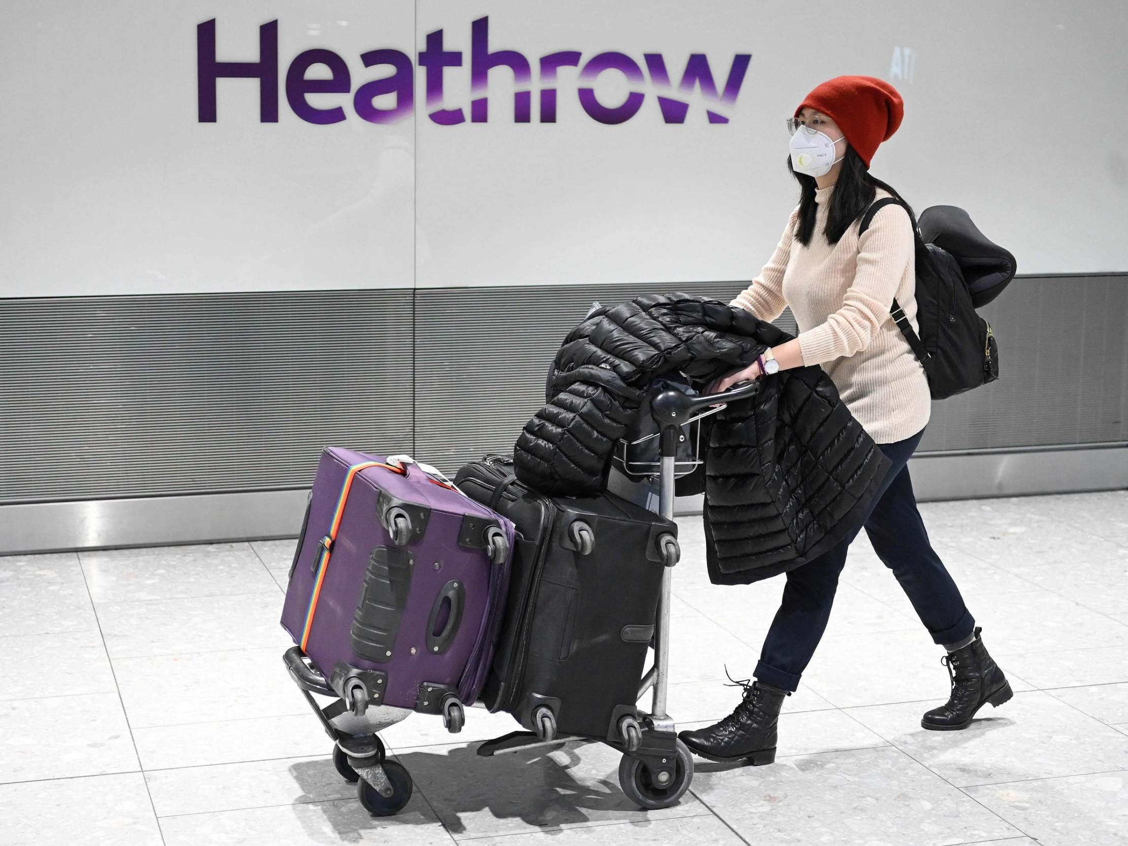 A passenger wearing a face mask arrives at Heathrow Airport