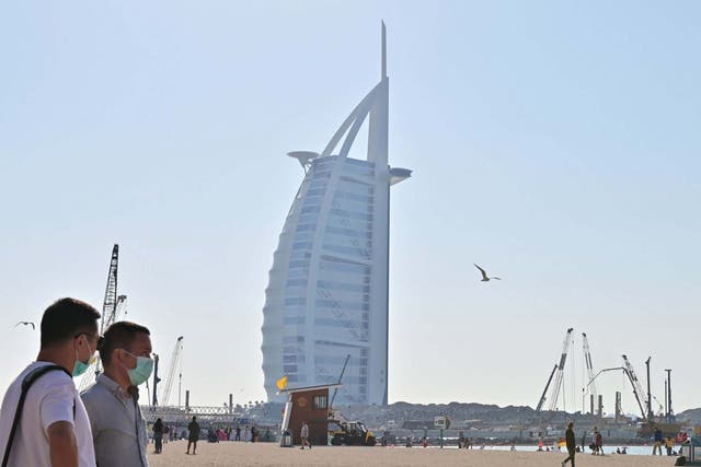 Tourists wearing surgical are pictured on a beach next to Burj Al Arab in the UAE