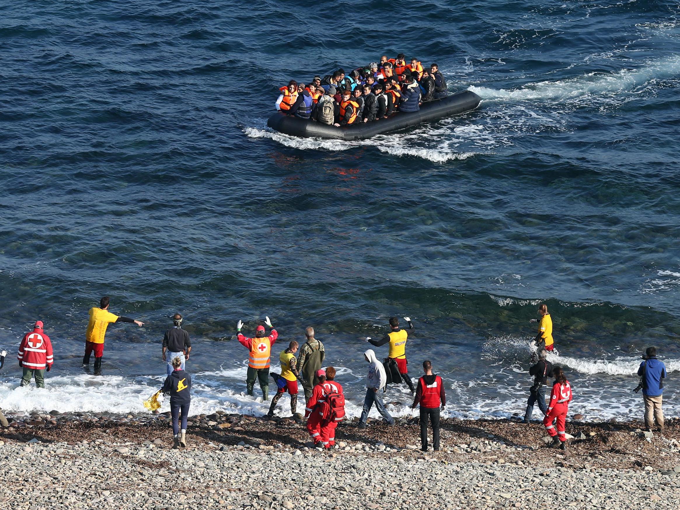 Aid workers gesture at a migrant boat as it approaches shore after making the crossing from Turkey to the Greek island of Lesbos on 17 November, 2015, in Sikaminias, Greece.