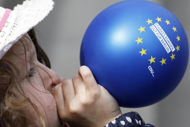 A child blows up a balloon during a pro-European Union rally in Berlin