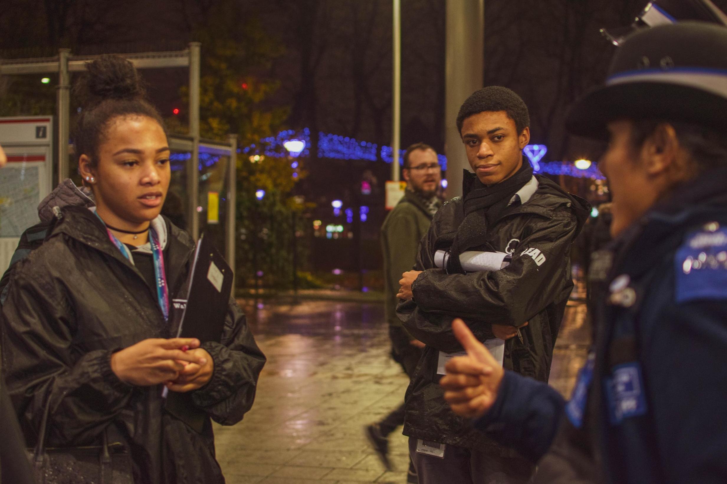 Thompson, left, and another Streetbase member interact with a uniformed police officer while on patrol (Loui Beggache)