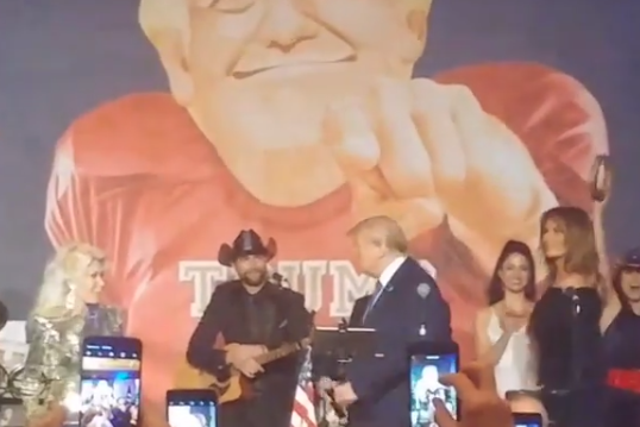 Donald Trump walks beneath a backdrop portraying himself as an American football player