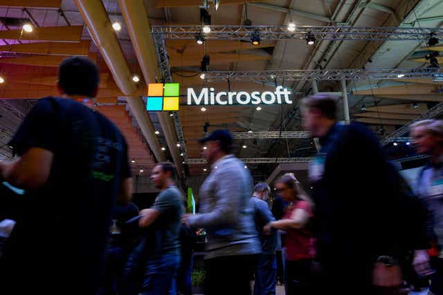 Attendees walk past the logo of US multinational technology company Microsoft during the Web Summit in Lisbon on November 6, 2019