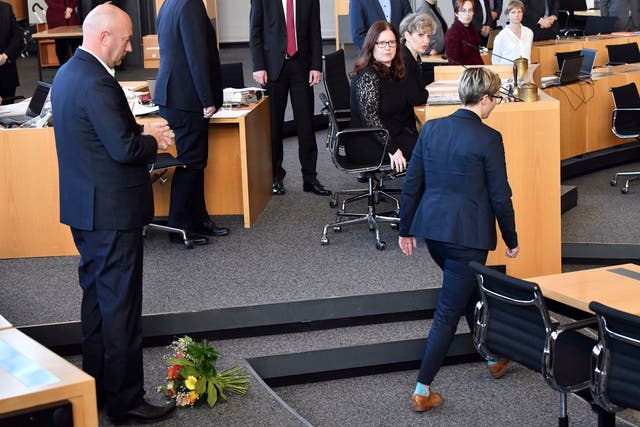 Die Linke's Susanne Hennig-Wellsow, right, walks away from Thomas Kemmerich of the FDP, after throwing a bouquet of flowers in front of him