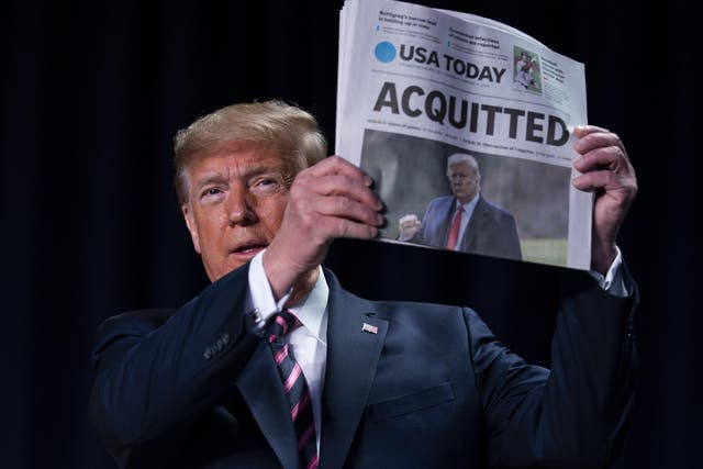 resident Donald Trump holds up a newspaper with the headline that reads "ACQUITTED" at the 68th annual National Prayer Breakfast, at the Washington Hilton, Thursday, Feb. 6, 2020, in Washington.