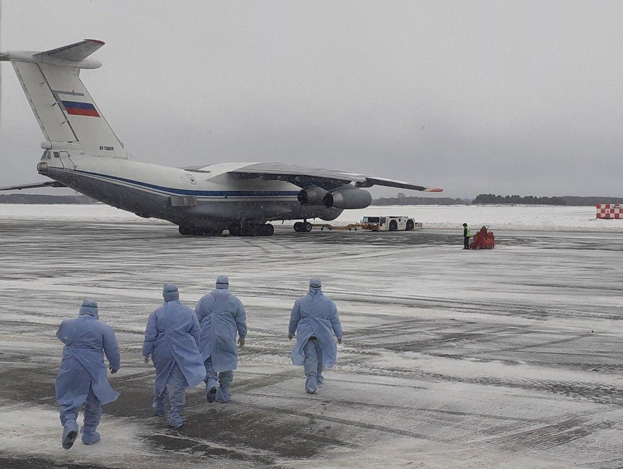 Military in protection gear approach the Ilyushin 76 jet on arrival in Tyumen airport