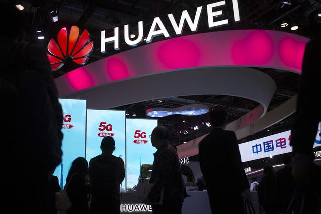 In this Oct. 31, 2019, file photo, attendees walk past a display for 5G services from Chinese technology firm Huawei at the PT Expo in Beijing.