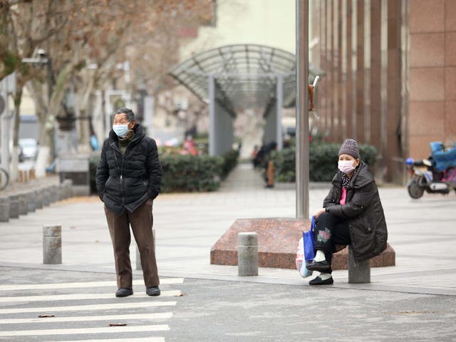 People wearing face masks are seen on the roadside following an outbreak of the novel coronavirus in Wuhan